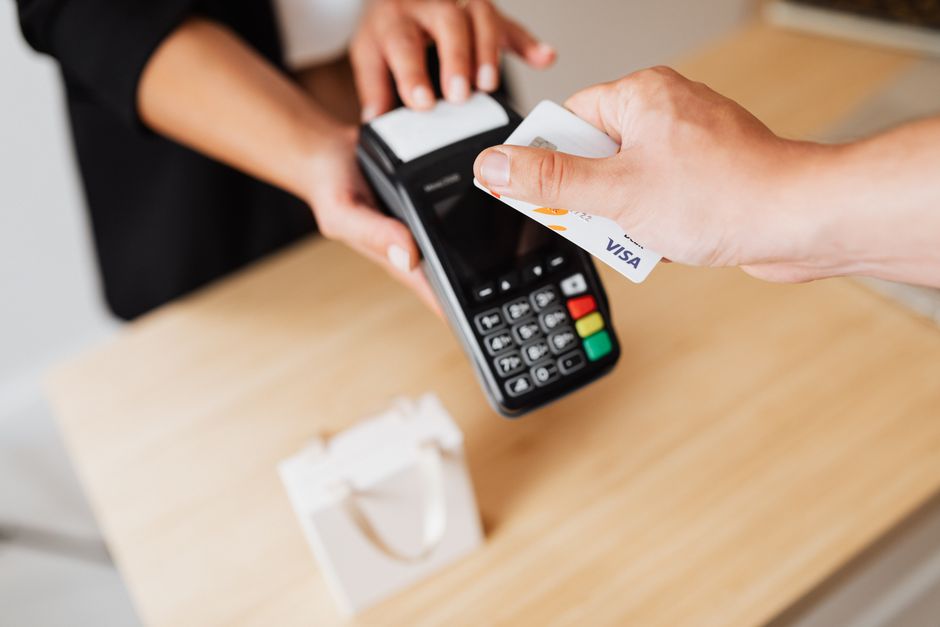 Customer tapping a Visa card on a payment terminal held across a counter