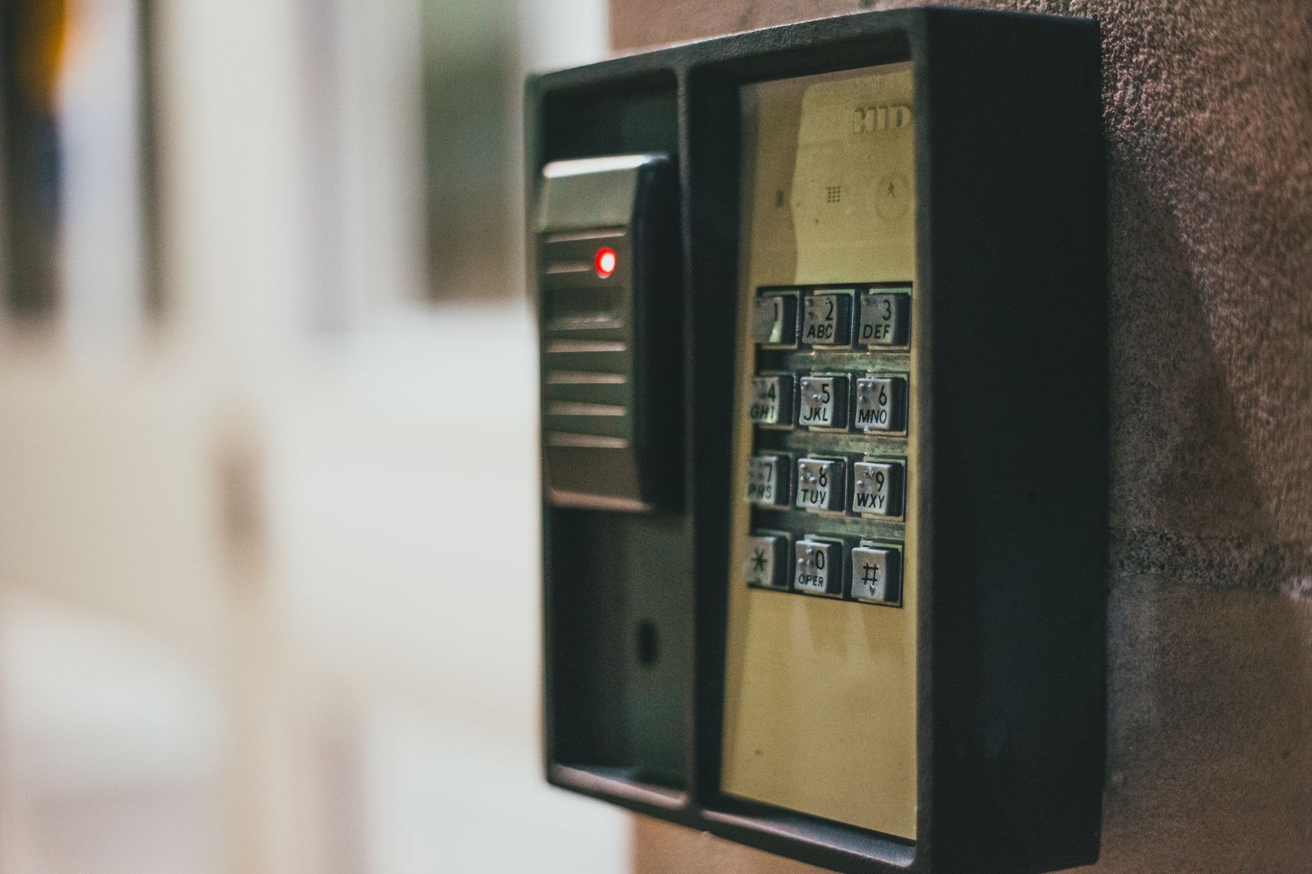 Wall-mounted access keypad with a card reader and a red indicator light